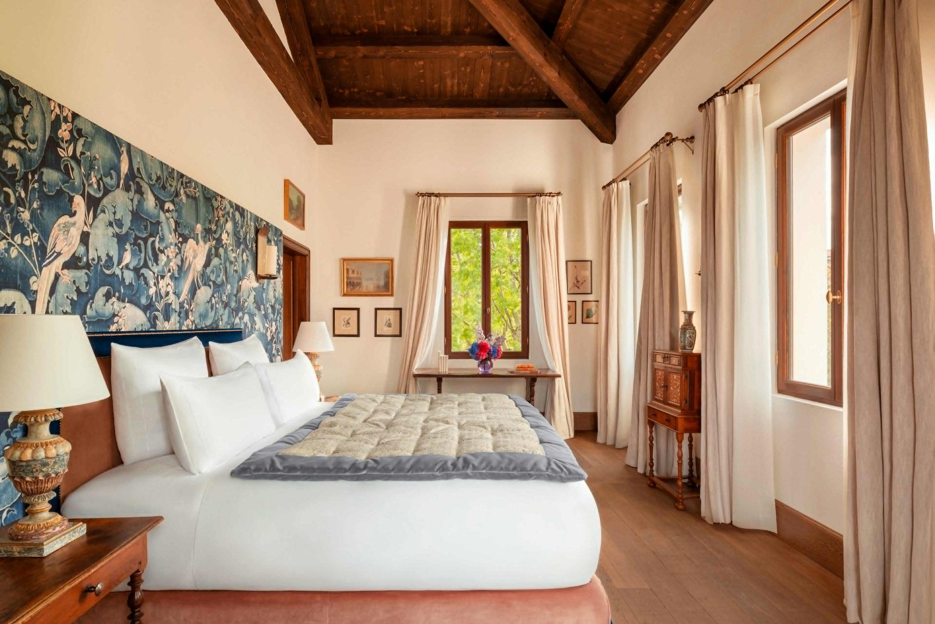 A room at Airelles Palladio Venezia with a beamed ceiling, tapestry headboard wall, and garden views